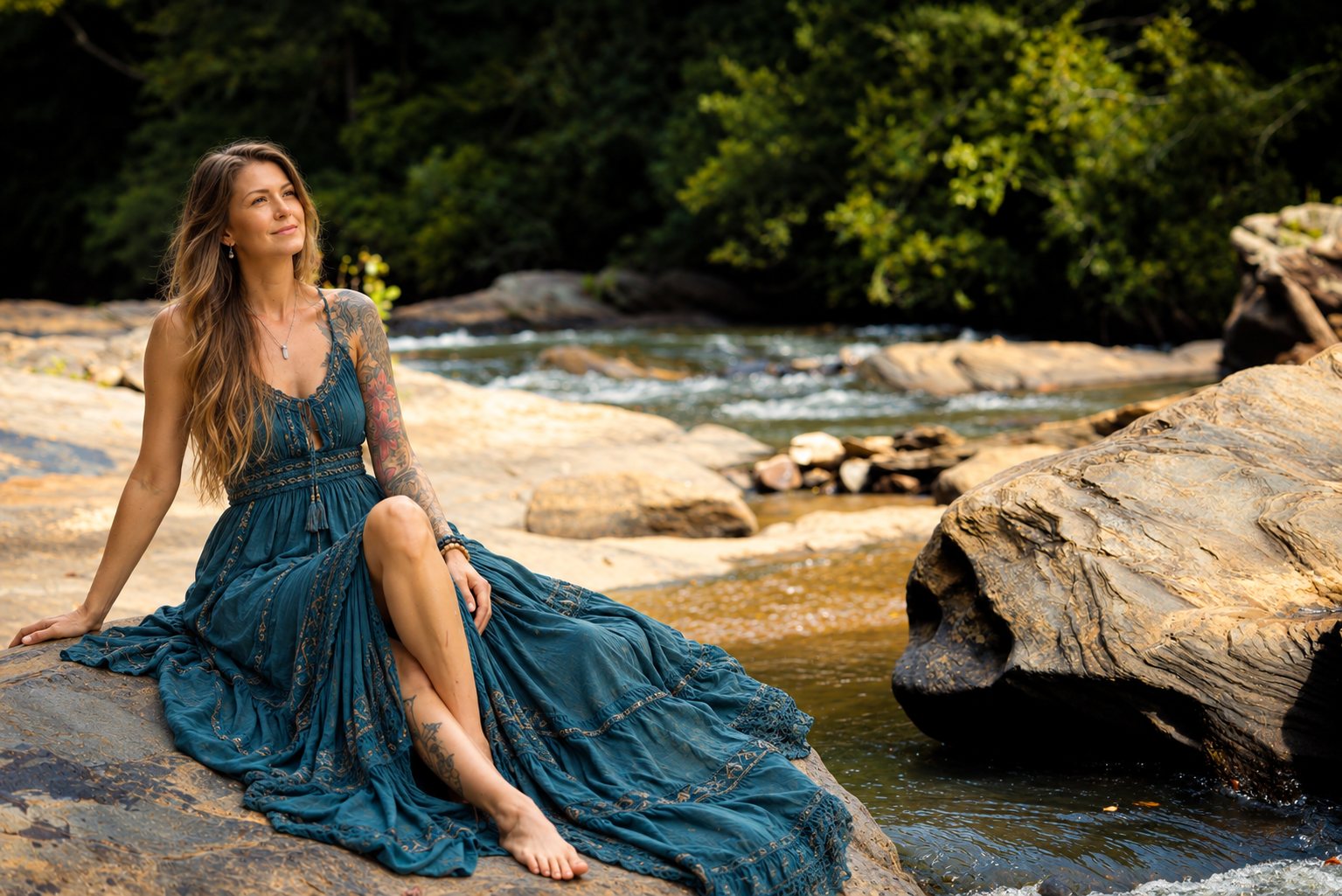 Staci Freed seated on sunlit rocks beside a flowing river